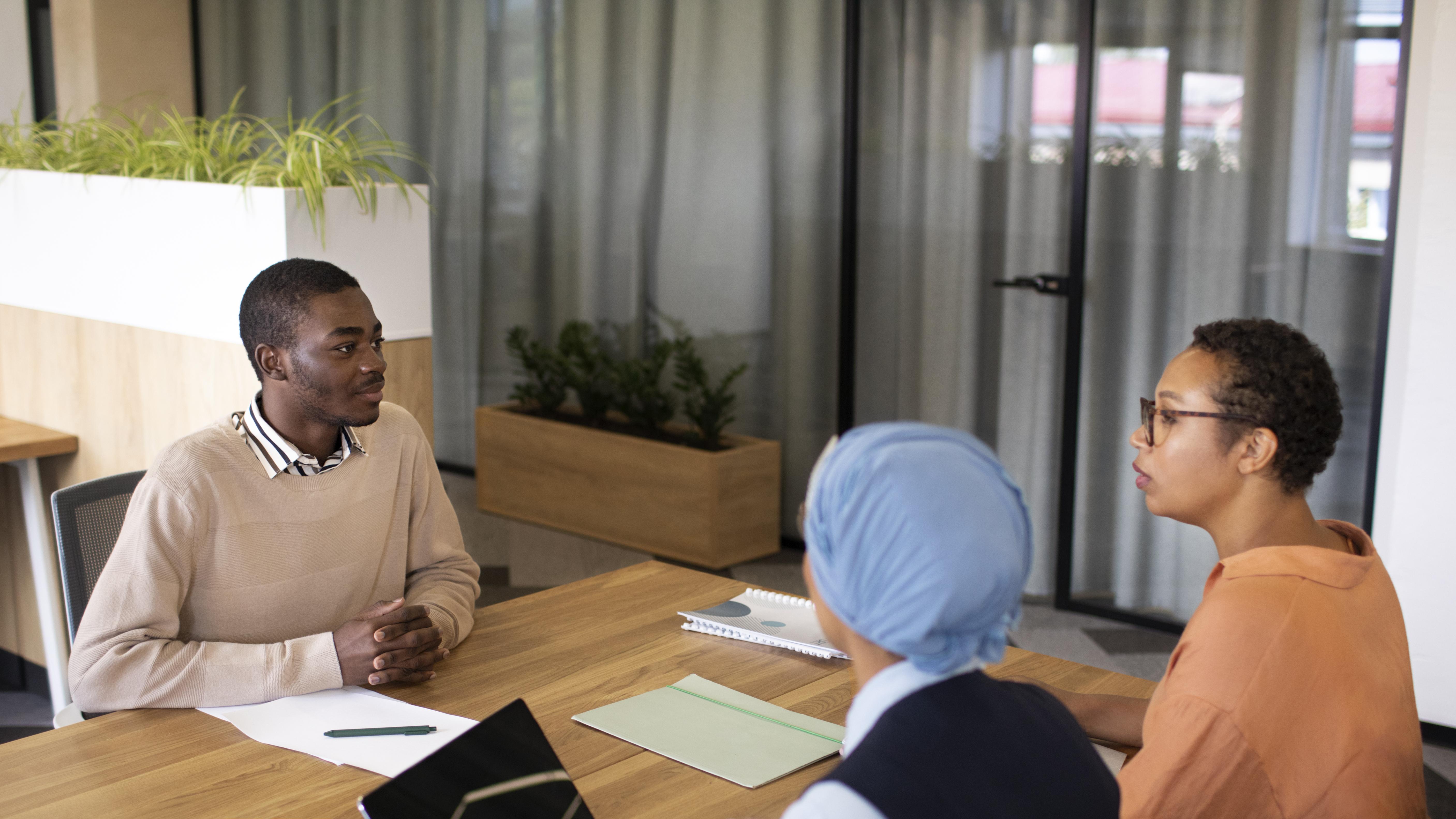 man-sitting-down-office-job-interview-desk-with-his-employers